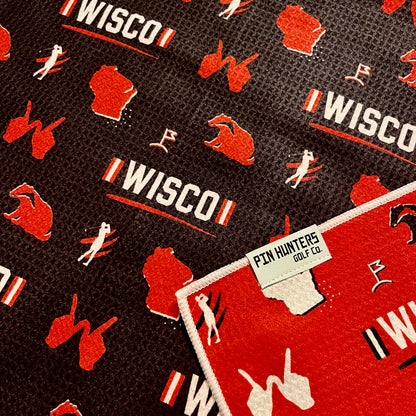 Close up of Wisconsin Badgers golf towel with black, red, and white Wisco, badger, Wisconsin state, golfer, and golf flag graphics.
