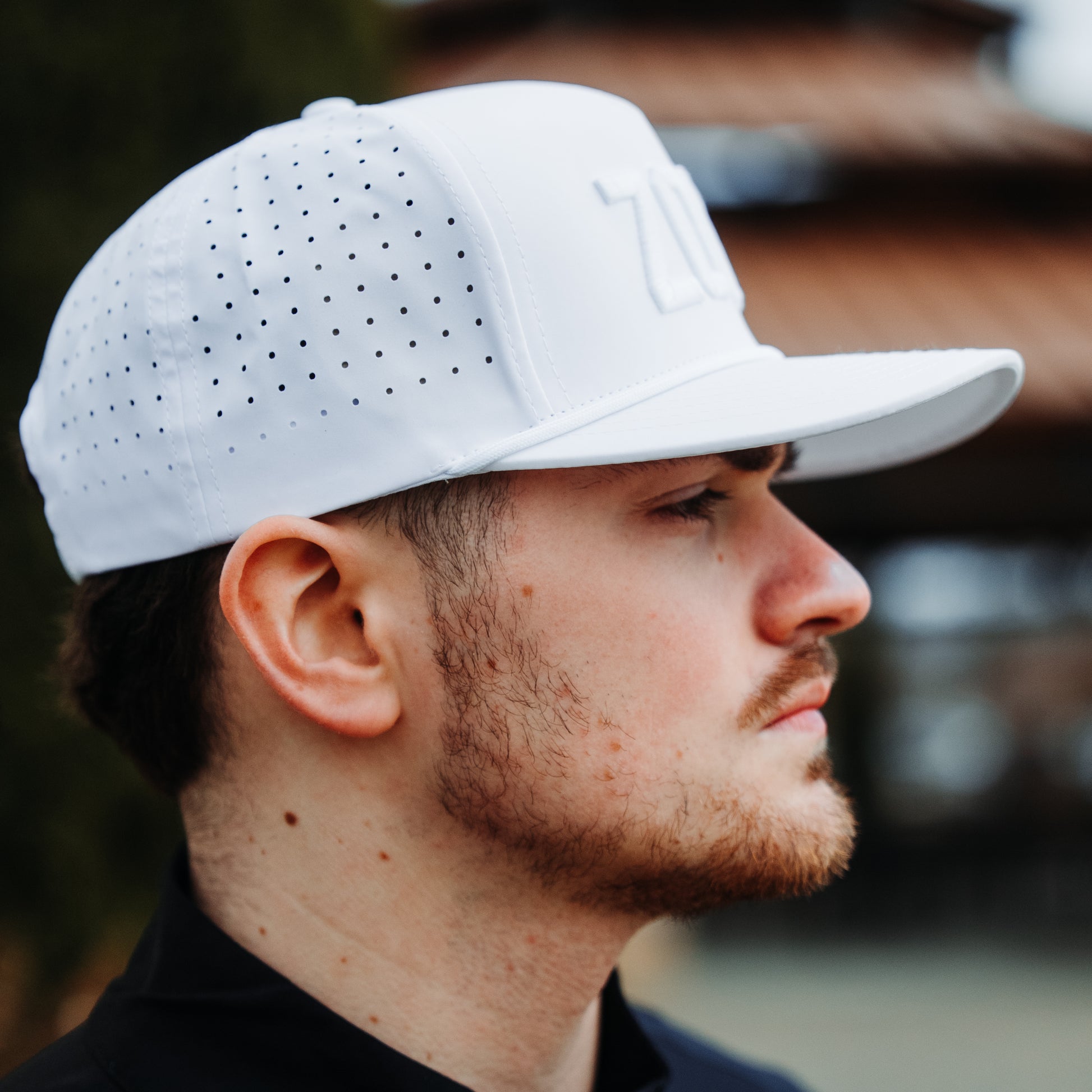 Whiteout Zona performance hat side profile with tonal white front embroidery, perforated side panels, white flat brim, and lifestyle model view.